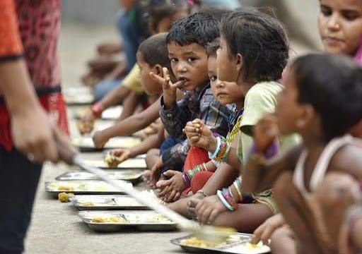 Children sitting in a row, eating a meal